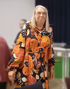 Frau Halle in einem orangenen Blumenkleid bei ihrer kleinen Ruhestandsfeier