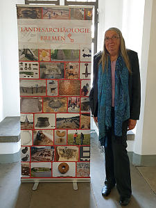 Ein Foto von Uta Halle neben einem Banner der Landesarchäologie